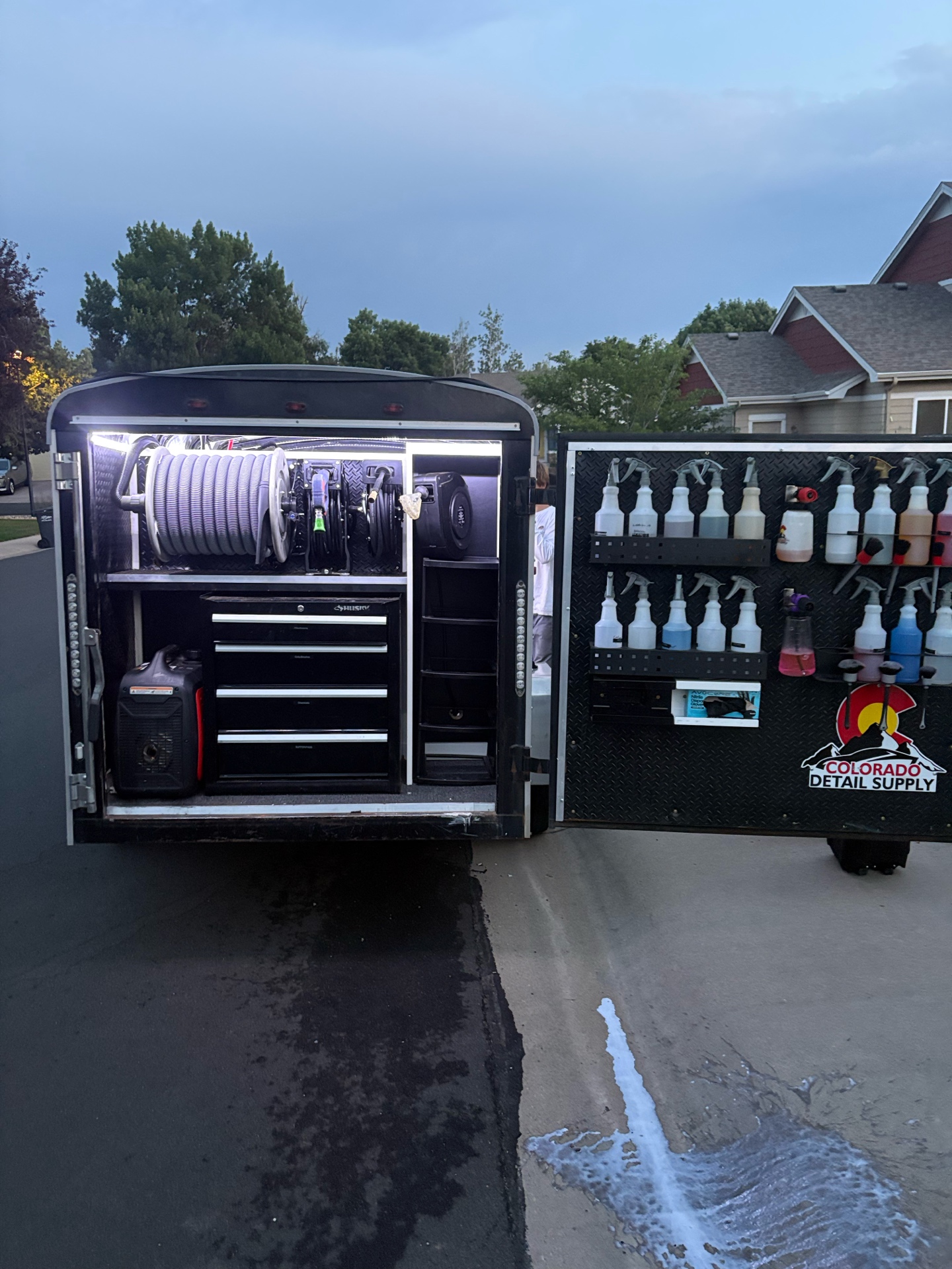 Open mobile detailing trailer with organized equipment and chemicals